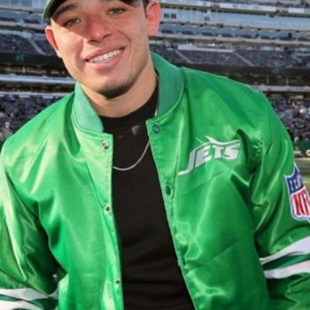 Person wearing a green sports team jacket and cap in a stadium setting