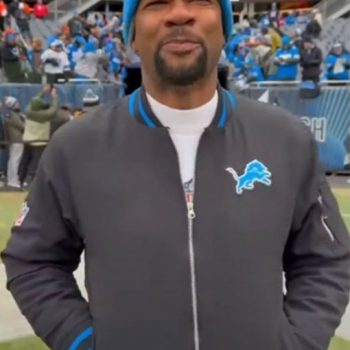 Person wearing a Detroit Lions jacket and blue beanie at a sports event
