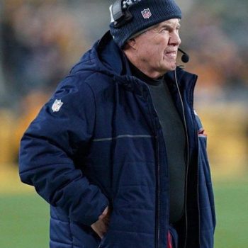 Person wearing a blue jacket and beanie with a headset on a sports field